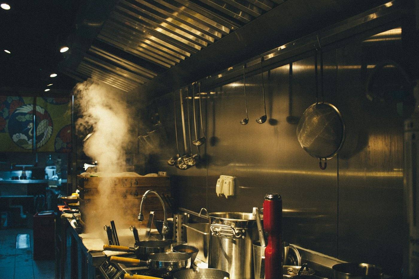 Stainless-steel commercial kitchen line with exhaust hood and cooking range